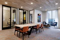 Contemporary office lounge with a long conference table, stylish chairs, and modern artwork.