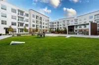 Modern apartment complex with a large, lush lawn and outdoor seating area | Caroline at Memorial | Houston, Texas