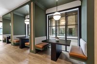 Modern seating alcove with elegant green walls, sleek black tables