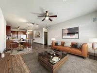 Modern open-concept living room with stylish furniture, wood flooring, and a cozy kitchen, perfect for relaxation and entertaining.