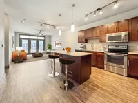 Modern open-concept apartment with gourmet kitchen, chic living area, and natural light streaming through large windows.