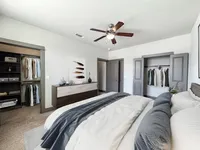 Elegant master bedroom with plush bedding, expansive closets, and stylish decor featuring modern furniture and neutral tones.