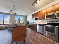 Modern open-concept apartment with sleek kitchen, hardwood floors, and a cozy living area with city views.