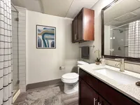 Modern and elegant bathroom featuring a sleek vanity, contemporary artwork, and a spacious glass shower enclosure.