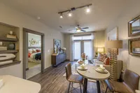 Cozy open-plan living room with elegant decor, featuring a stylish dining area, inviting bedroom view, and abundant natural light through large windows.