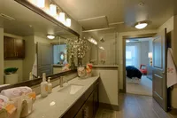 Luxurious bathroom with elegant vanity, modern lighting, and spacious shower, leading to a serene bedroom.