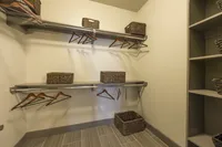 Spacious walk-in closet with elegant shelving, sleek accents, and stylish wicker storage baskets.