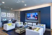 Modern entertainment and workspace area with cozy seating, wall-mounted TV, and computer stations, ideal for relaxation and productivity.