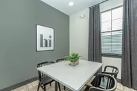 Modern dining area with stylish gray walls, elegant black chairs, and a chic framed artwork.