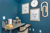 Charming home office with teal walls, vintage rotary phone, sleek wooden desk, and modern art accents for a cozy work environment.