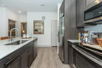 Modern kitchen with sleek dark wood cabinets, granite countertops, and stainless steel appliances, perfect for culinary enthusiasts.