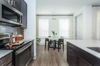 Modern kitchen with sleek cabinetry and granite countertops leading to a cozy dining area with natural light and contemporary decor.