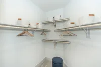 Spacious walk-in closet featuring modern shelving, elegant wooden hangers, and stylish white storage baskets.
