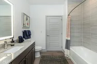 Elegant modern bathroom featuring a sleek granite countertop, stylish dark wood cabinets, and a cozy bathtub.