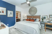 Modern bedroom with stylish decor, blue accent wall, and cozy ambiance, featuring a comfortable bed, elegant art pieces, and a charming workspace.