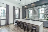 Contemporary kitchen with stylish pendant lighting, sleek countertops, and modern bar stools, featuring large windows and elegant tile patterns.
