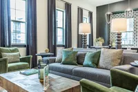 Elegant modern living room with stylish gray sofa, plush green armchairs, and cozy lighting, creating a warm and inviting atmosphere.