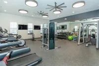 Modern fitness center with state-of-the-art gym equipment, featuring treadmills, exercise bikes, weight machines, and free weights in a spacious, well-lit room.
