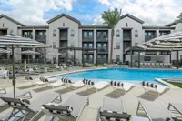 Luxurious apartment complex featuring a shimmering outdoor pool, stylish lounge chairs, and modern architecture, perfect for relaxing and unwinding.