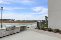 Scenic waterfront patio featuring a modern outdoor grill, perfect for al fresco dining with sweeping views of the river.