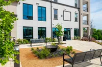 Contemporary apartment exterior featuring landscaped gardens, stylish benches, and large glass windows providing natural light.