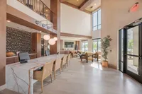 Elegant lobby area with high ceilings, modern lighting, and stylish seating, featuring a sleek marble reception desk under warm, natural lighting.