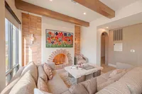Inviting living room with cozy beige sofas, vibrant floral artwork, and a charming arch-brick fireplace.