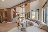 Elegant and spacious modern living area with high ceilings, featuring a chic marble counter, stylish seating, and ample natural light from large windows.