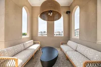 Chic balcony with elegant arched windows, cozy seating, and a modern coffee table, offering a picturesque view of the surrounding architecture.