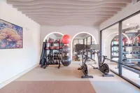 Modern fitness room featuring sleek exercise bikes, stylish equipment, and beautifully designed wavy ceiling panels.