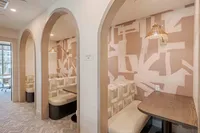 Elegant communal seating area with arched entries, cozy booth seating, and abstract wall design perfect for social gatherings.