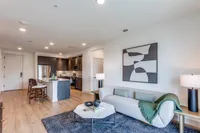 Modern open-plan apartment with stylish kitchen, cozy living area, and elegant decor featuring a gray couch and abstract artwork.
