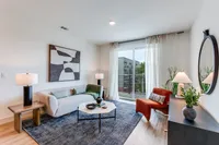 Chic and modern living room with stylish decor, featuring a comfortable sofa, elegant artwork, and large windows offering natural light and a balcony view.