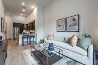 Elegant open-concept living space with sleek modern kitchen, cozy sofa, and stylish decor, perfect for relaxing and entertaining.
