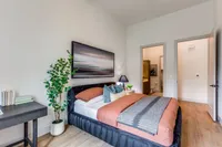 Inviting bedroom with modern decor, featuring a plush bed, cozy pillows, stylish artwork, and warm hardwood flooring.