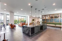 Luxurious open-concept living space featuring modern kitchen island, elegant seating, and floor-to-ceiling windows with scenic views.