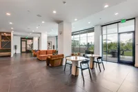 Elegant communal lounge with modern seating and chic dining tables, offering a bright, welcoming ambiance and seamless access to outdoor patio space.