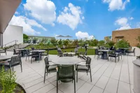 Stunning rooftop terrace featuring elegant outdoor seating, lush greenery, and a vibrant blue sky backdrop.