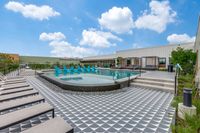 Luxurious outdoor pool area with stylish lounge chairs and private cabanas under a bright blue sky.