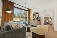 Bright and inviting living area with modern decor, featuring a plush sofa, elegant armchair, and a stunning view through large glass doors leading to a private outdoor oasis.