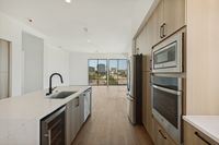 Modern open-concept kitchen with sleek appliances and stunning city view through floor-to-ceiling windows.