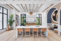 Modern communal lounge with elegant decor, featuring sleek ceiling beams, stylish wall art, and abundant natural light from large windows.