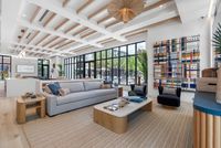 Luxurious and modern living room with floor-to-ceiling windows, elegant decor, and vibrant artwork, offering a bright and inviting atmosphere.