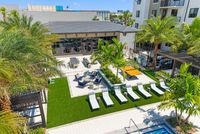 Luxurious outdoor lounge area with palm trees, sun loungers, and a barbecue setup, perfect for relaxation and entertaining.