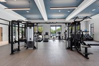 Modern fitness center with state-of-the-art equipment, large windows offering natural light, and views of a tranquil outdoor pool area.