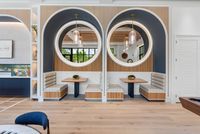 Chic and modern dining nook with elegant circular mirrors, plush seating, and stylish lighting.