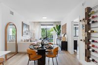Bright, modern living area with elegant decor, featuring a cozy sofa, stylish dining set, wine rack, and lush outdoor view through sliding glass doors.