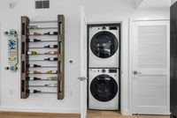 Contemporary apartment interior featuring a sleek stacked washer and dryer, a stylish wooden wine rack, and vibrant skateboard art.