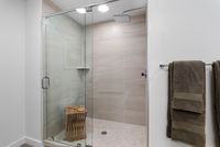Luxurious modern shower with glass doors and elegant tiled walls, featuring sleek fixtures and plush towels for a spa-like experience.