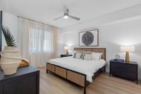 Inviting bedroom with elegant decor, natural light, and modern ceiling fan, offering a tranquil retreat.